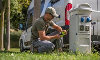 Caucasian Men in His 30s Attaching Camper Van Electric Plug to RV Park Hookup Tower. Camping Feature Theme.